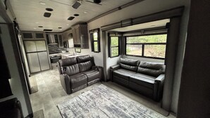Ein modernes Wohnmobil-Interieur mit einer Küchenzeile, einer Sitzecke mit Fenster und einem Deckenventilator.