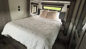 Ein Schlafzimmer mit einem großen Bett, einem Fenster und einer Tür.