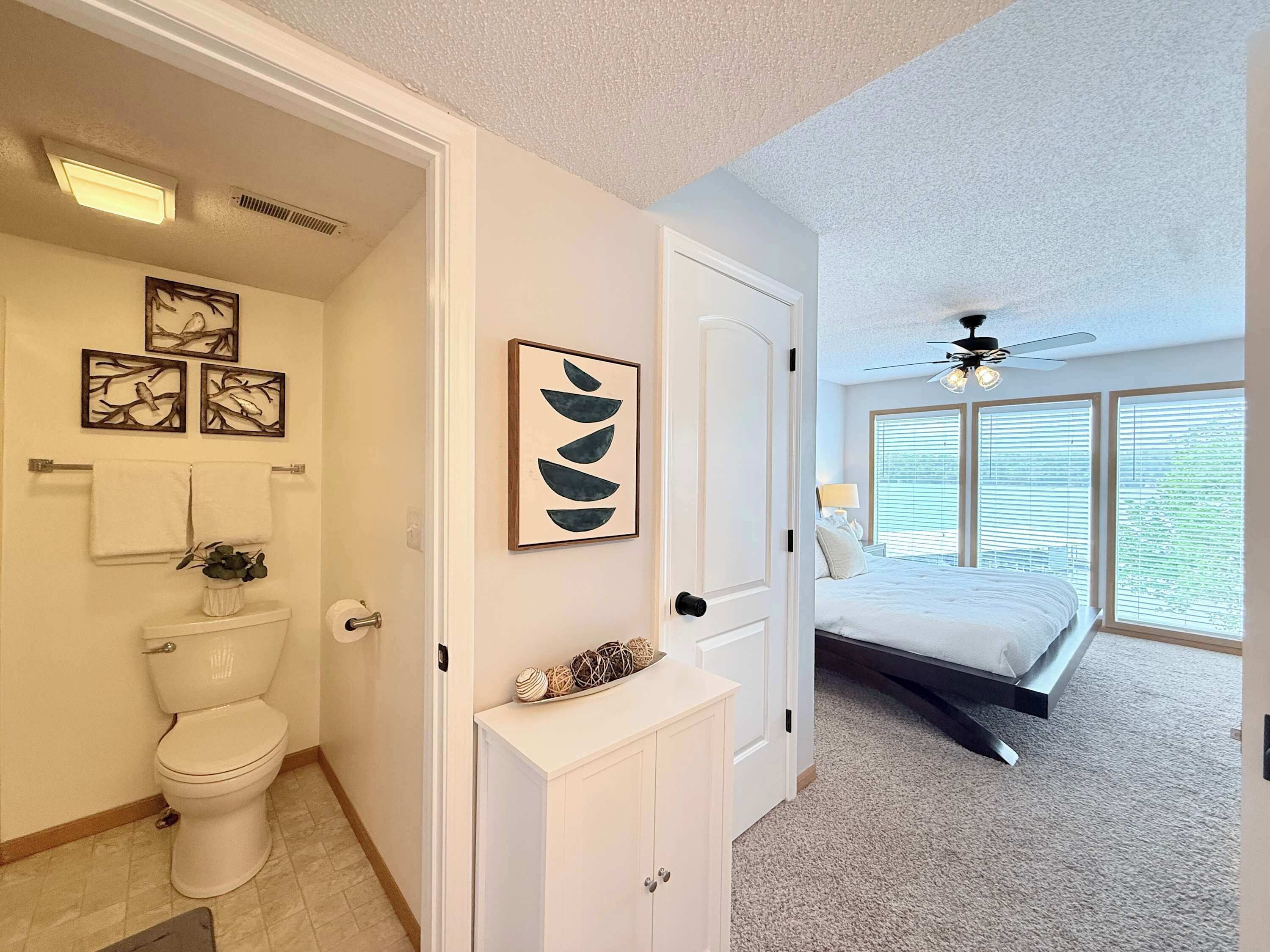 A bathroom with a toilet, towel rack, and framed artwork.