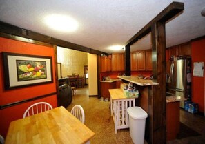 Eine kleine Küche mit Holzausstattung, einem Kühlschrank und einem Essbereich mit Tisch und Stühlen.