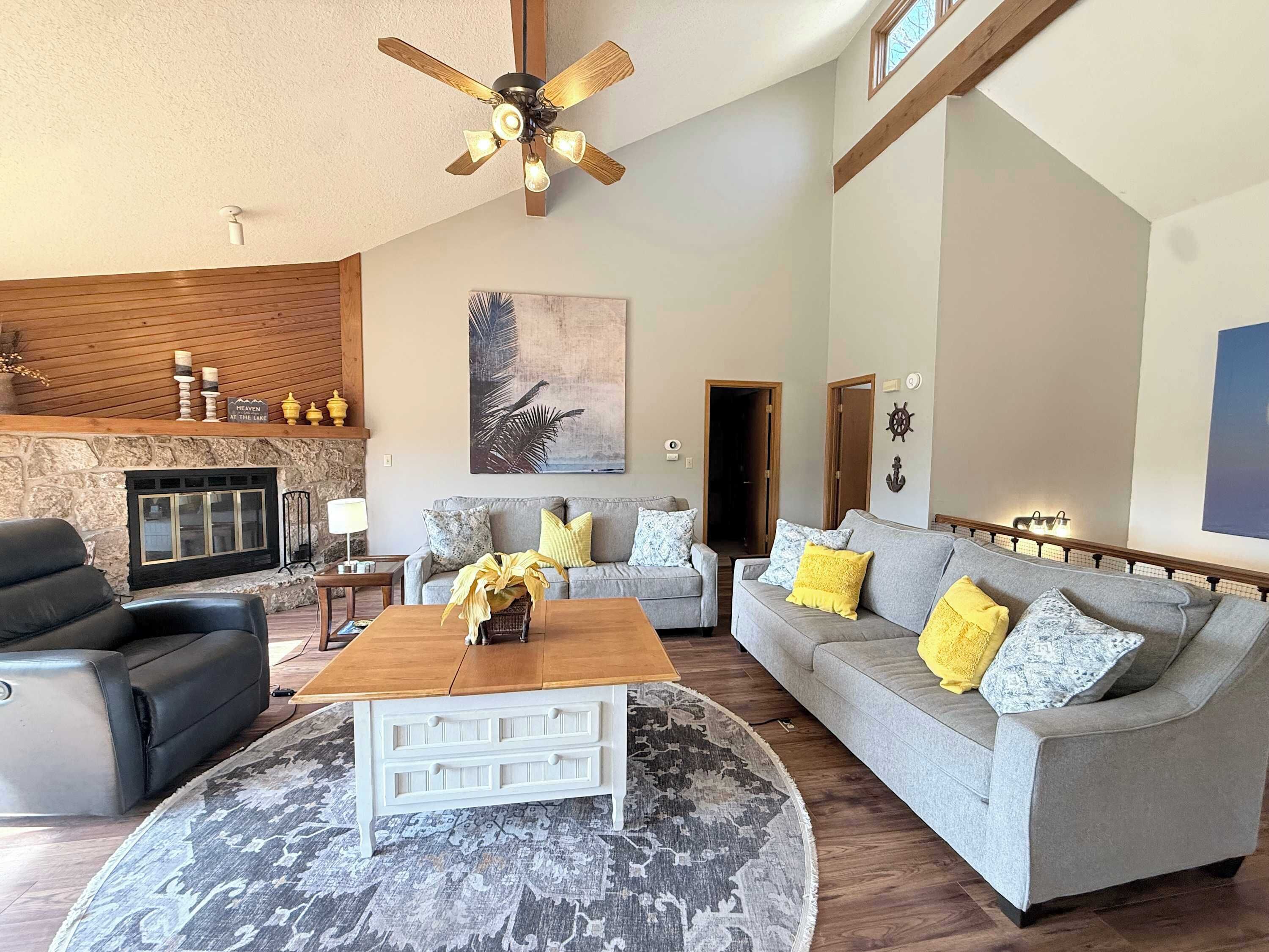 A living room with a fireplace, a ceiling fan, a sofa set, and a coffee table.