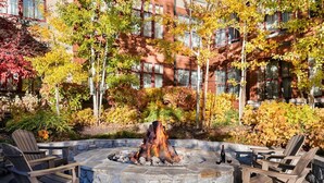 A stone fire pit with chairs around it, surrounded by autumn foliage and a building in the background. - Beautiful spacious 2-bedroom condo in fabulous South Lake Tahoe (South Lake Tahoe)