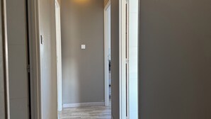 Ein Korridor mit Holzboden, weißen Wänden und einer Decke mit freiliegenden Balken.