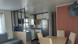 Um espaço compacto com cozinha americana, área de refeições com mesa e cadeiras, um sofá e uma pequena janela.