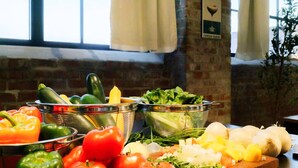 Una encimera de cocina con diversas verduras y un colador.