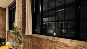Una habitación con paredes de ladrillo, un ventanal grande, una planta y un globo terráqueo sobre una mesa.