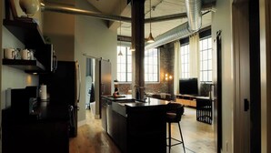 Een moderne keuken met een centraal eiland, een zithoek met een bank en een groot raam dat voor daglicht zorgt.