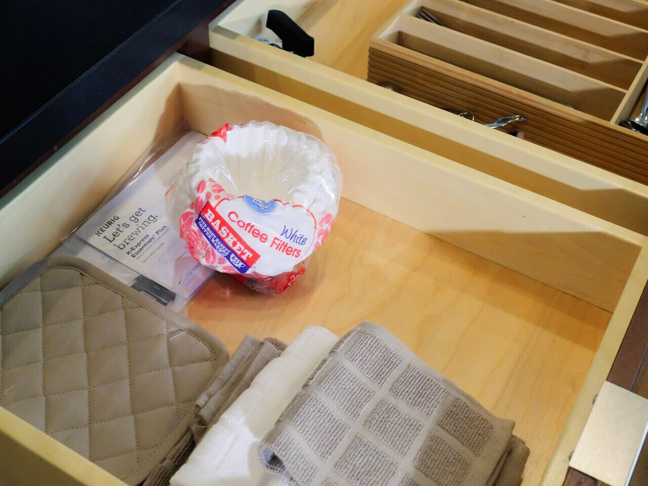 Un tiroir contenant un sachet de filtres à café, un sac matelassé et une serviette pliée.