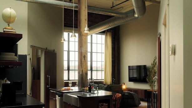 Una cocina moderna con una isla central, un área de comedor con un sofá y un televisor montado en la pared.