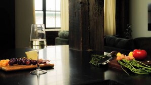 Una mesa de comedor con una copa de vino, queso, uvas y verduras.