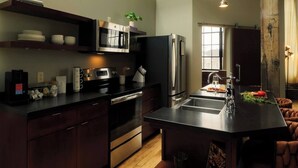 Una cocina moderna con electrodomésticos de acero inoxidable, una isla central con pileta y un comedor con vista a la ciudad.