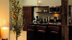 Una cocina moderna con una isla central, taburetes de bar y una planta grande.