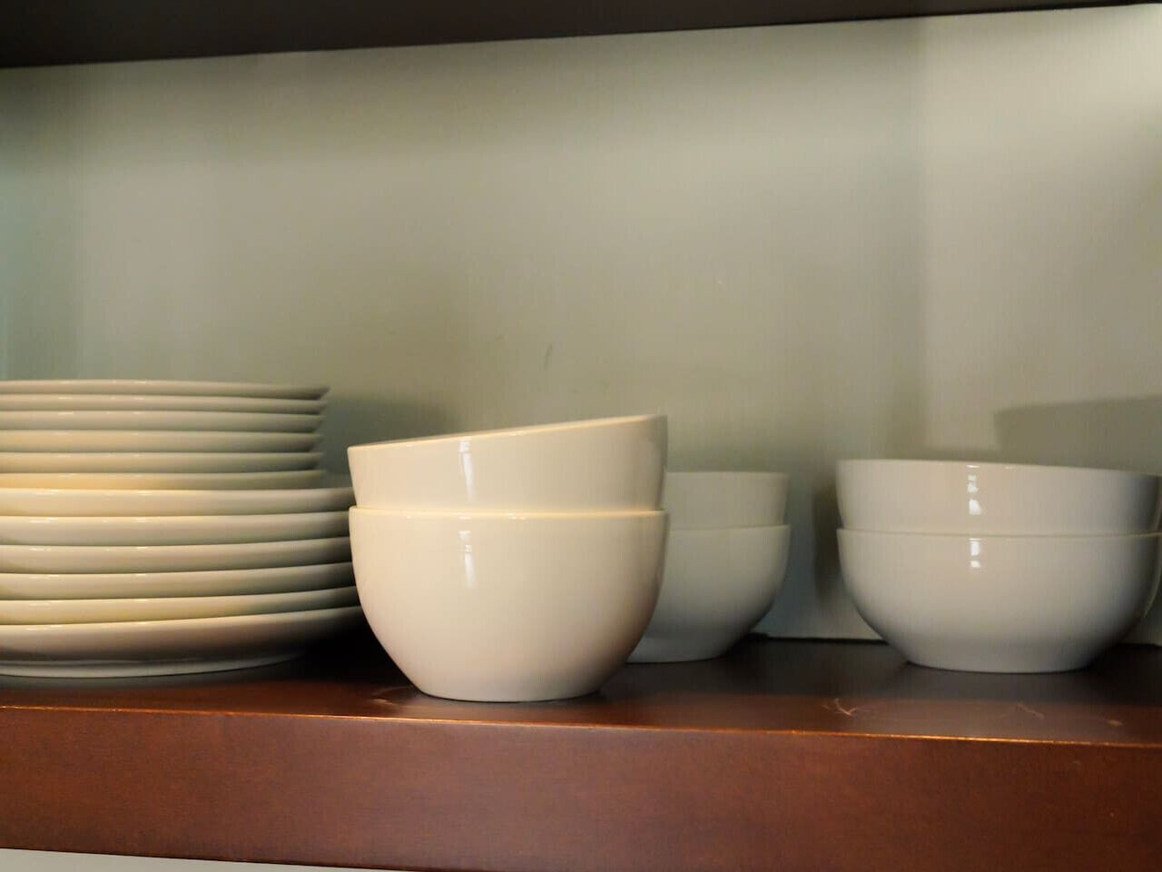 Uma bancada de cozinha com pratos e tigelas empilhados.