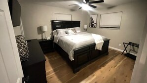 A bedroom with a bed, nightstands, a ceiling fan, and a dresser.