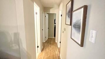 A hallway with wooden flooring, white walls, and framed pictures.