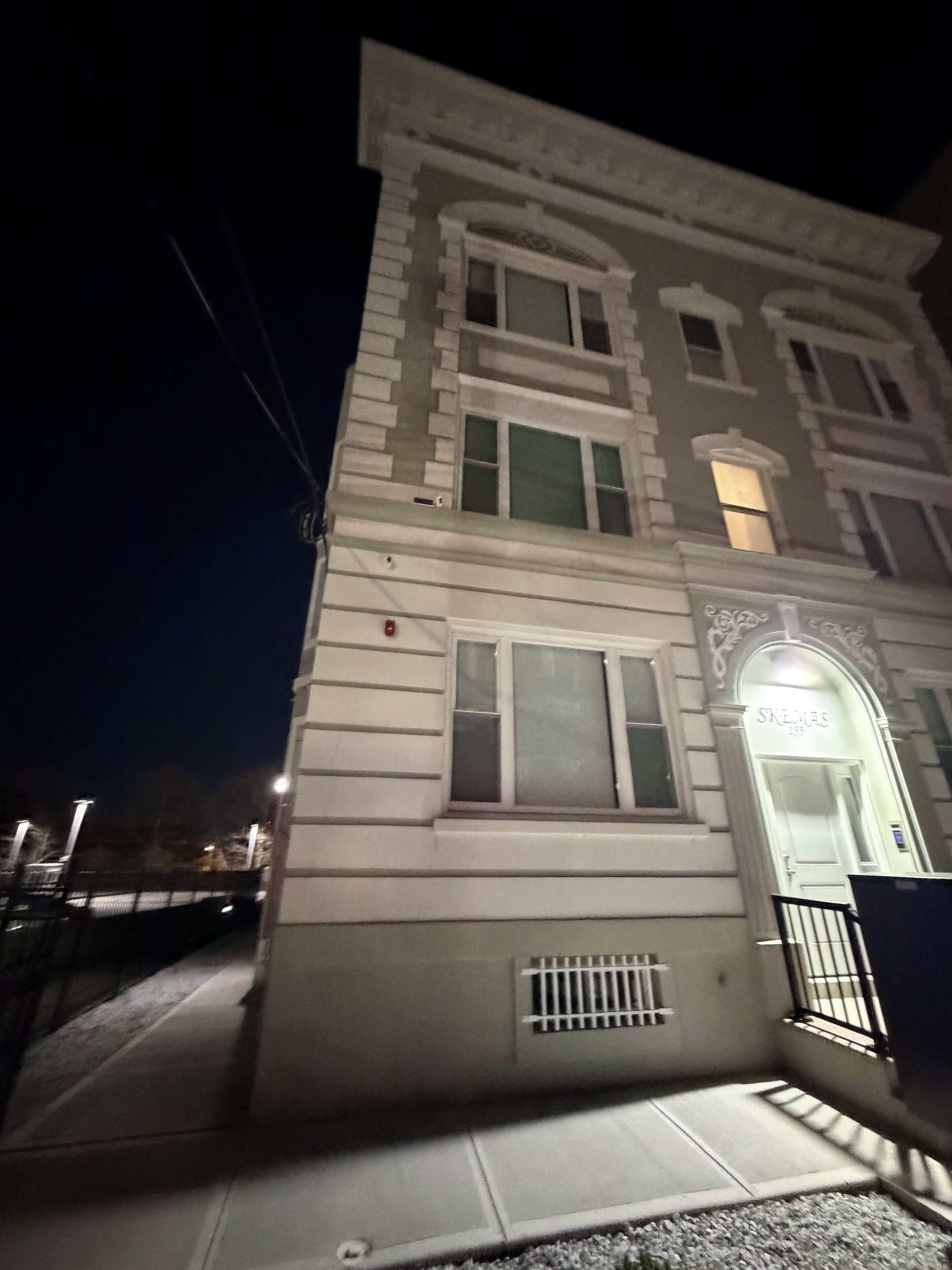 A multi-story building with a classic architectural style, featuring a prominent entrance with a door labeled 'SNEVMA 135'.