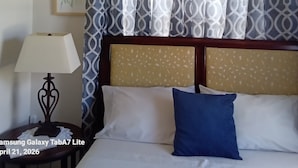 Una habitación de hotel con una cama, una mesita de noche, una lámpara y una cortina estampada.