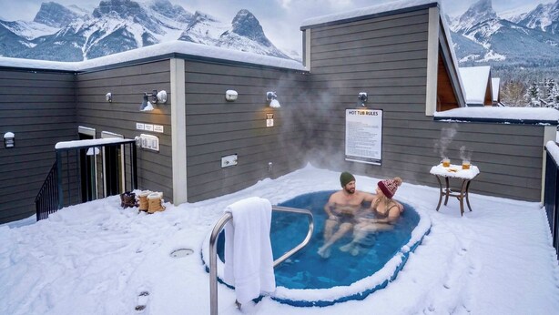 A hot tub in a snowy outdoor setting with mountains in the background. - Summit View Penthouse in Downtown Canmore at Brookside Lane (Canmore)