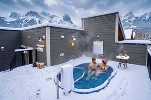 A hot tub in a snowy outdoor setting with mountains in the background. - Summit View Penthouse in Downtown Canmore at Brookside Lane (Canmore)
