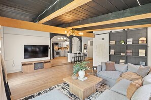 A modern living room with a large flat-screen TV, wooden coffee table, and a grey sofa. - Modern Pool Retreat Near Dallas & Stadium (Irving)