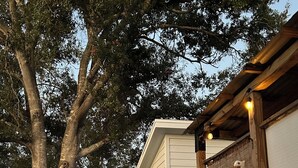 Une maison dotée d’un porche abrité, d’une clôture en bois et d’un chemin menant à l’entrée.