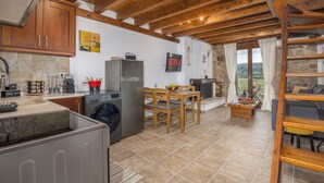 Une cuisine avec des poutres en bois, un lave-linge, un réfrigérateur et un coin repas avec une table et des chaises.