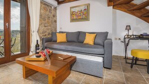 Un salon avec un canapé gris, une table basse en bois et une vue sur l’extérieur, visible à travers une porte vitrée.