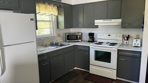 A kitchen with dark cabinets, a white refrigerator, a microwave, a stove, and a sink. - Cozy 3-bedroom cottage in Old Orchard Beach (Old Orchard Beach)