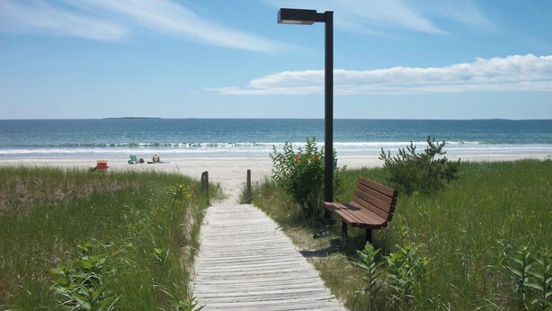 A wooden boardwalk leading to a beach with a bench and a street lamp. - Cozy 3-bedroom cottage in Old Orchard Beach (Old Orchard Beach)