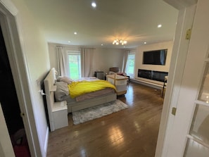 A bedroom with a bed, bedside table, TV, and a view of the outdoors. - World Cup 2026 Luxury HQ 5BR w/ Private Bath, Gym, 100” TV, Princeton & NJT (Princeton)