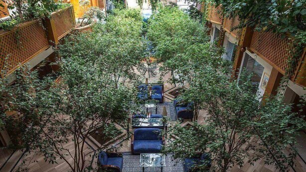 An indoor courtyard with seating areas, trees, and a view of the surrounding buildings.