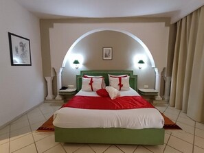 A hotel room with a large bed, two bedside lamps, a framed picture on the wall, and a window with curtains. - tunsia lodge Hotel  (Hammamet)