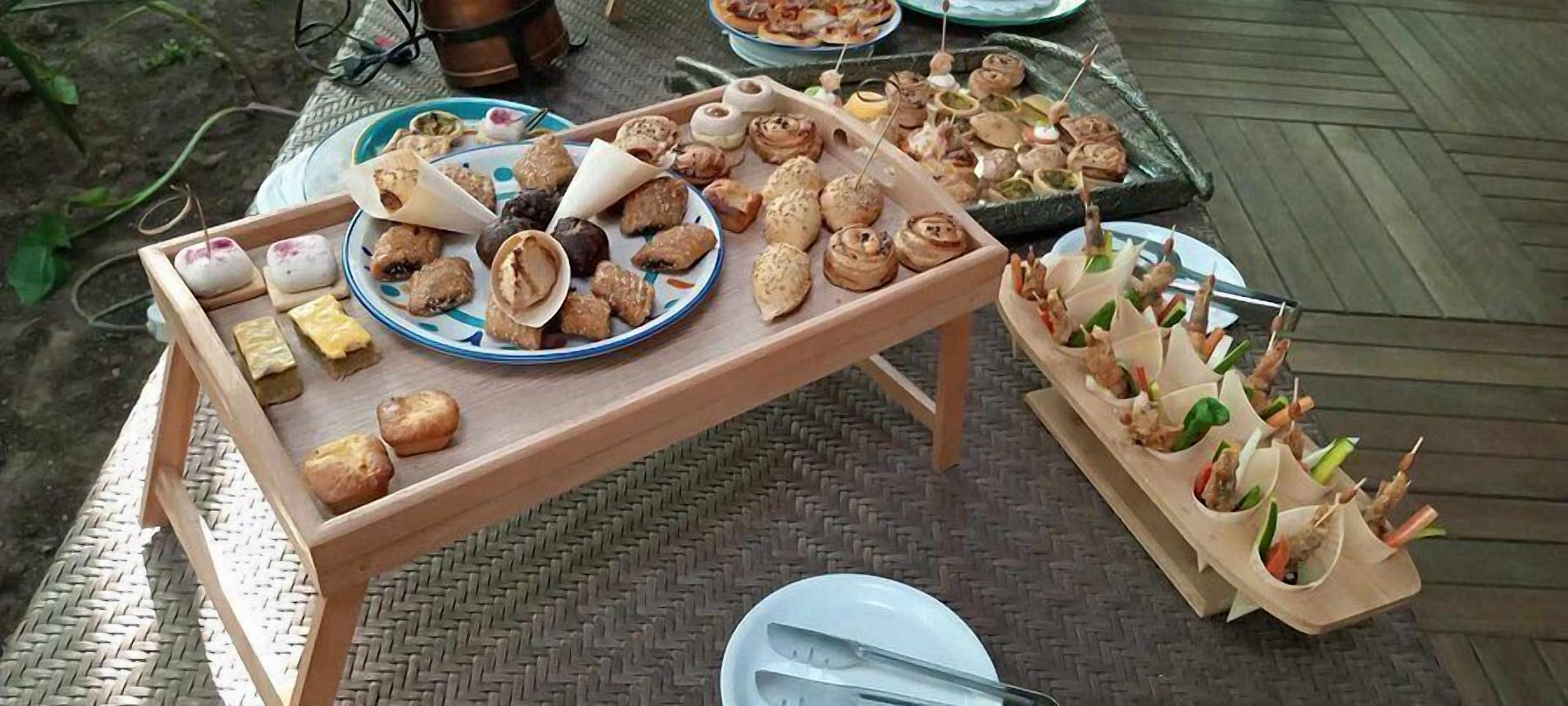A wooden table with various food items and a tray of appetizers.