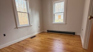Ein Zimmer mit Holzboden, zwei Fenstern und einer Tür.