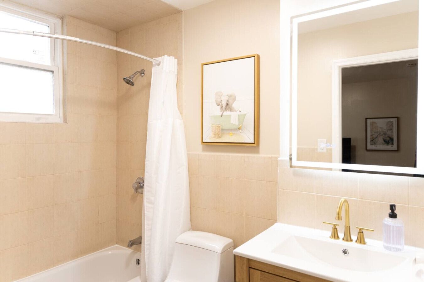 Un baño con bañera, inodoro, lavabo y un cuadro en la pared.