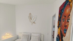 Un dormitorio con cama, almohadas, una lámpara de pared y un cuadro.