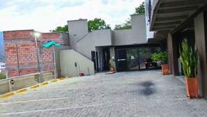 Un camino empedrado que conduce a una entrada con portón, un muro de ladrillo y una planta en maceta.