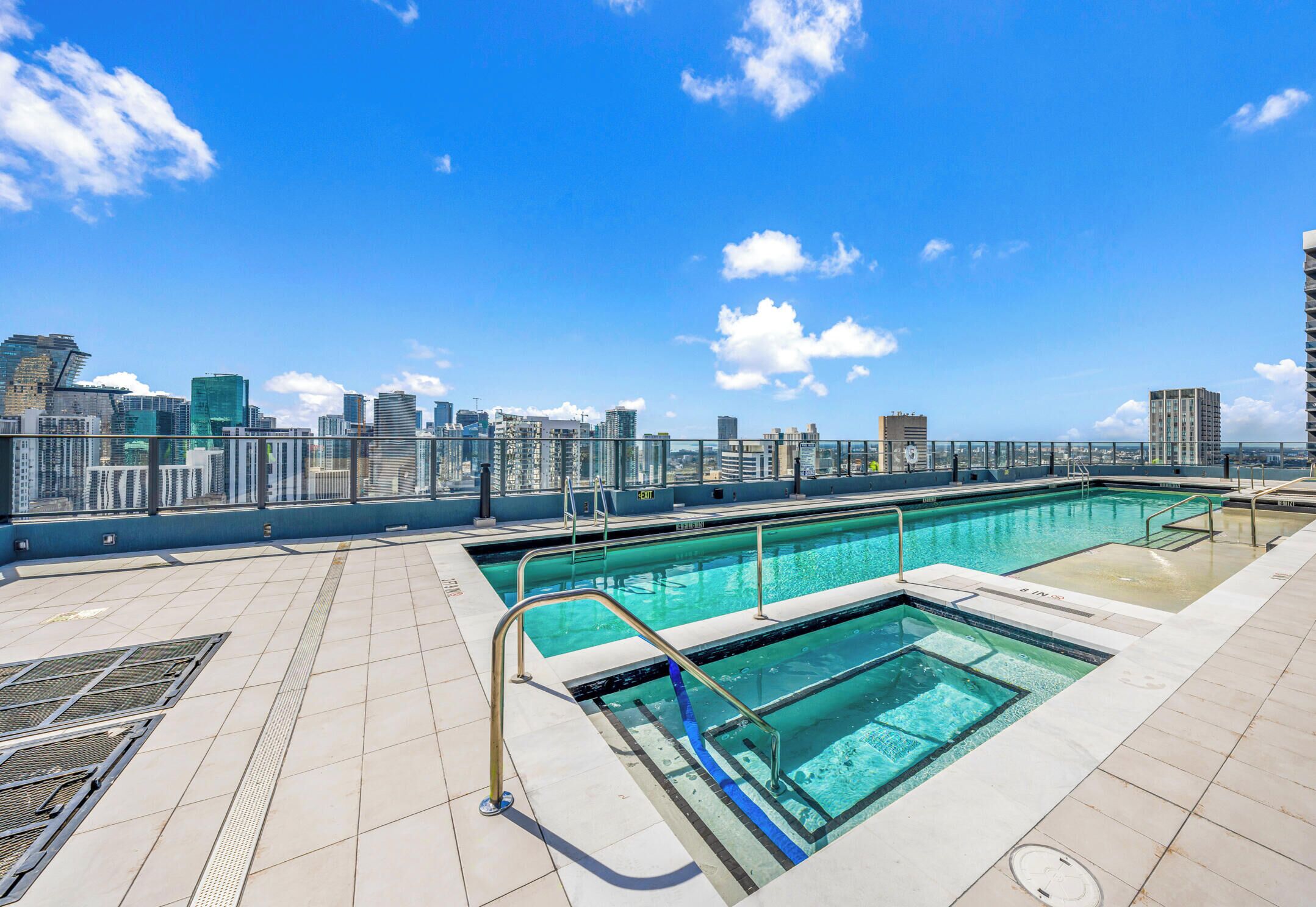 A rooftop pool with clear blue water, surrounded by a city skyline view.