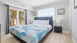 Ein Schlafzimmer mit Bett, Nachttisch, Fenster und Tür.