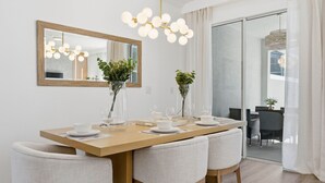 A dining area with a wooden table, white chairs, and a large mirror above. - Chic Family Retreat, Pool, Mario and Mickey Rooms (Davenport)