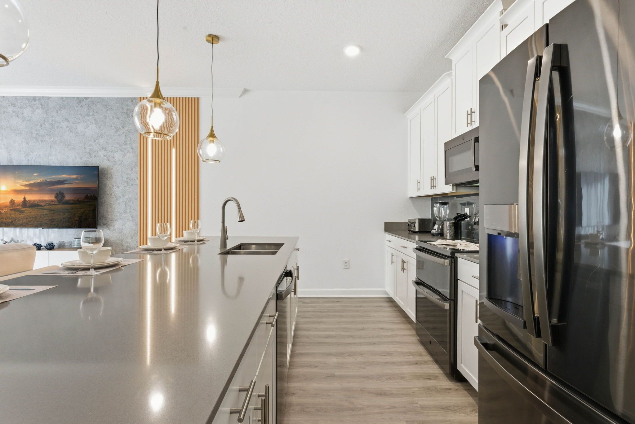 A modern kitchen with a large island, stainless steel appliances, and pendant lighting.