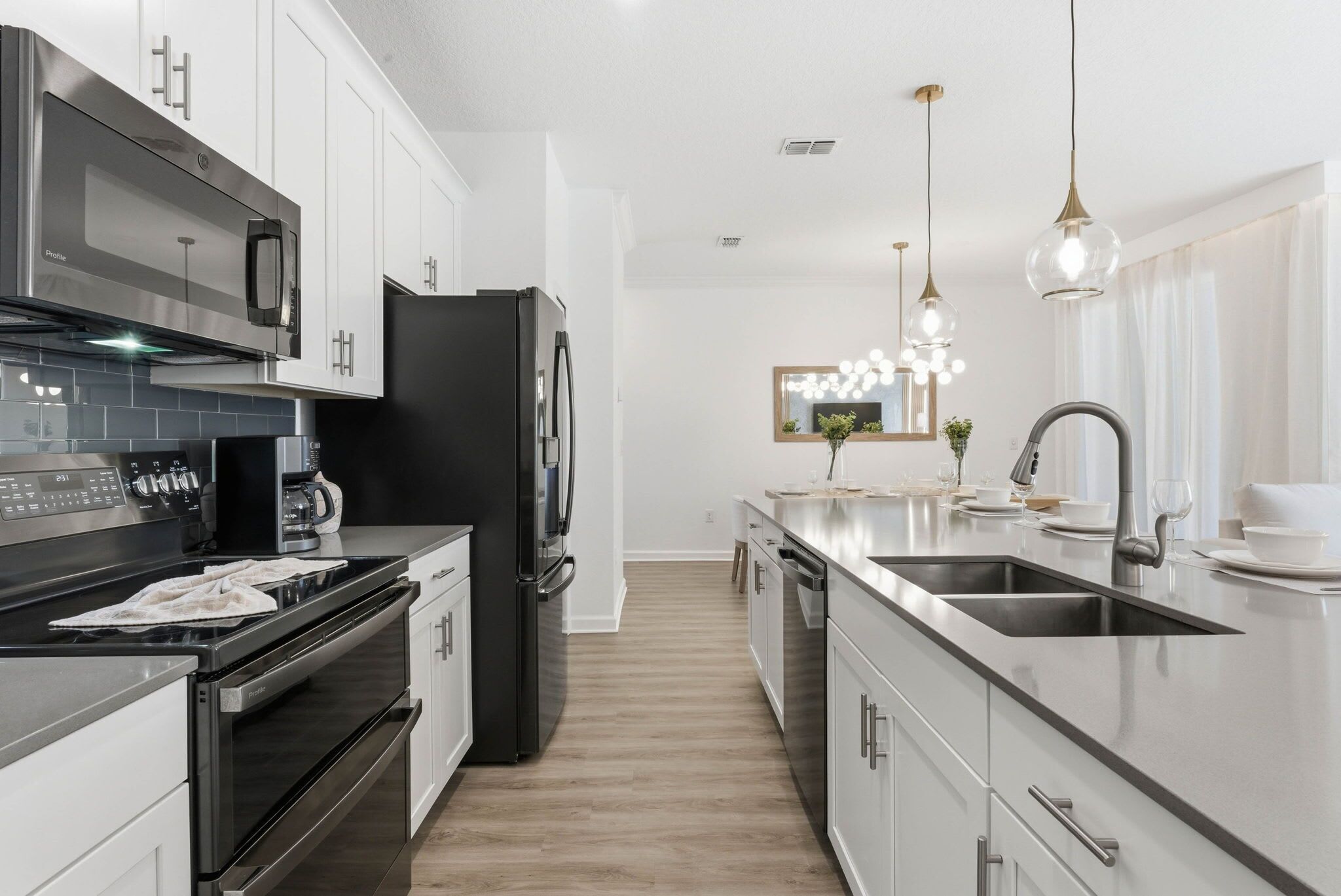 A modern kitchen with stainless steel appliances, a central island with a sink, and pendant lighting.