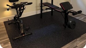 Ein Heimfitnessraum mit Fahrradergometer, Langhantelbank und Gewichtshebewerkzeug.
