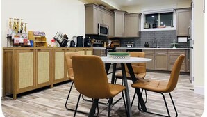 Eine moderne Küche mit Holzschränken, einer Mikrowelle und einem Essbereich mit rundem Tisch und Stühlen.