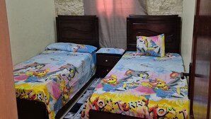 A bedroom with two beds, a stone wall, an air conditioning unit, and a curtain. - Star Apartment 2 Hurghada (Hurghada)