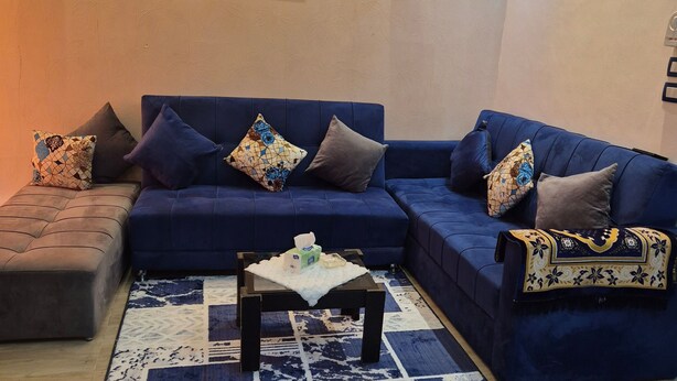 A living room with a blue sofa, patterned rug, and wall art. - Star Apartment 2 Hurghada (Hurghada)