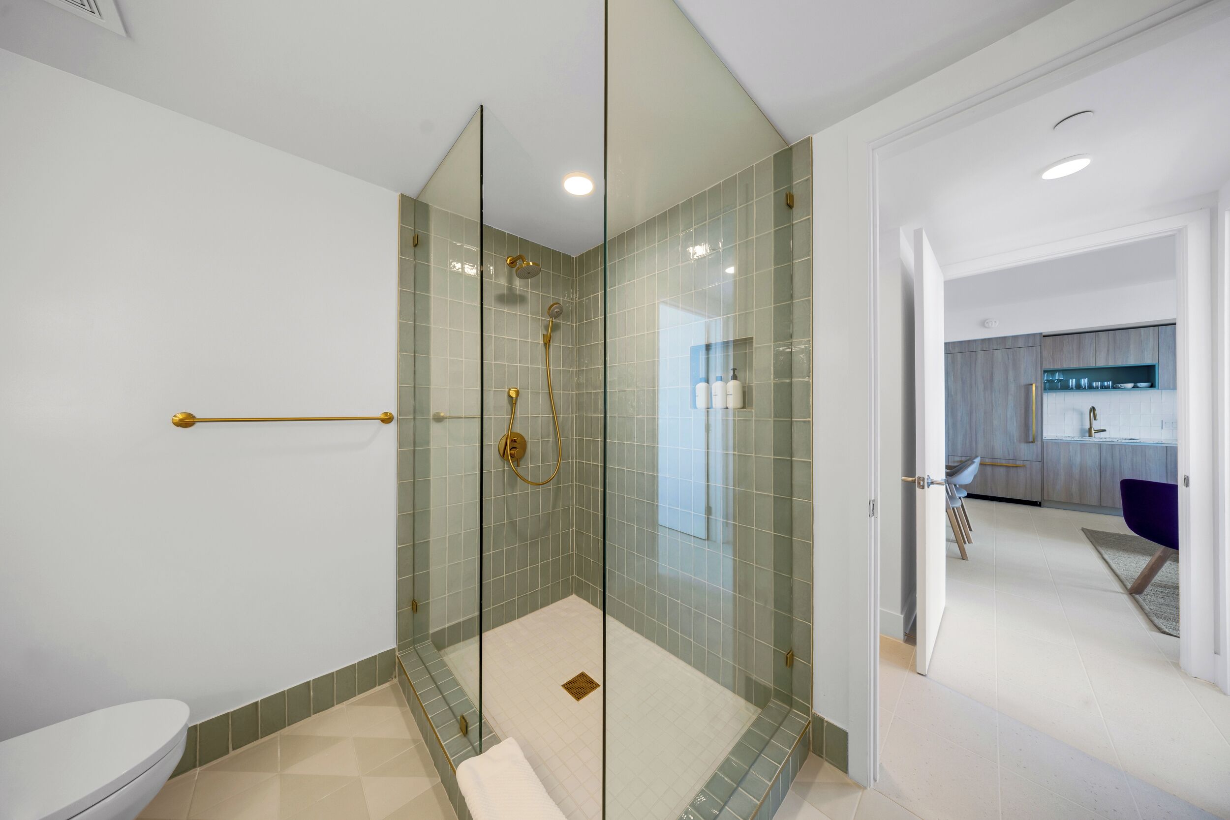 Ein modernes Badezimmer mit einer Glaskabine zur Dusche, Toilette und einem sichtbaren Waschbereich.