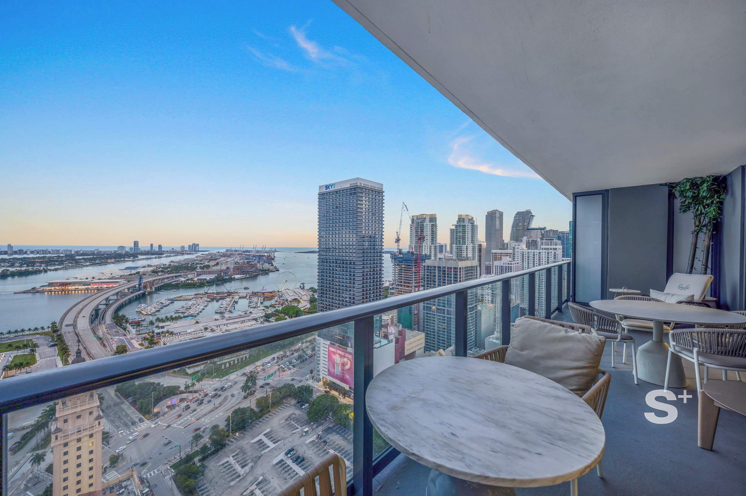 A balcony with a city view, including a marina and high-rise buildings.