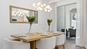 A dining area with a wooden table, white chairs, and a large mirror above. - Chic Family Retreat Pool Mario and Mickey Rooms (Davenport)