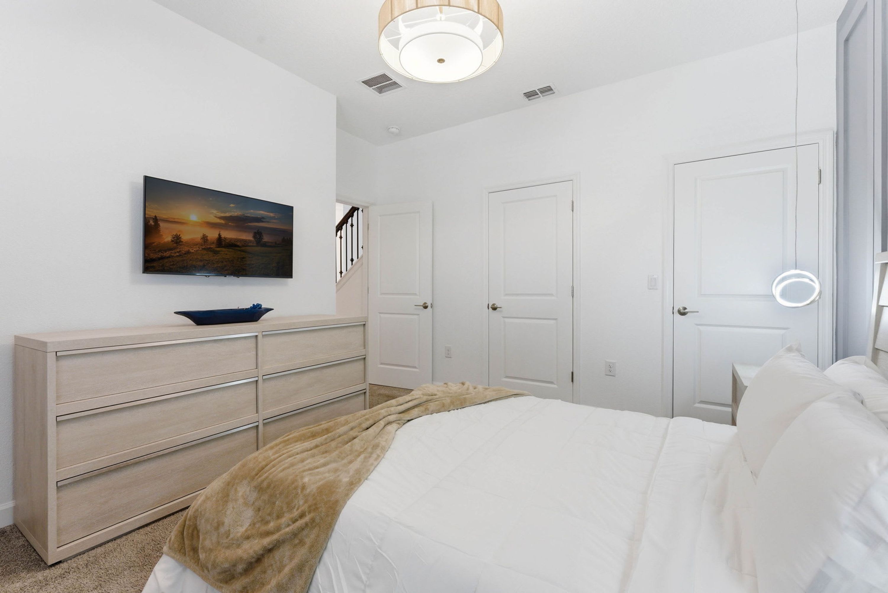Un dormitorio con cama, cómoda, cuadro y puerta.